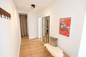 A hallway with wooden flooring, a mirror, a fluffy bench, and a painting of a bird. - **Private Mountain Retreat with Exceptional Panoramic Views for 4 persons** (Winterberg)