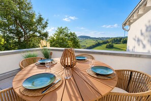 A round wooden table set for four with blue plates, a candle, and a bottle. - **Private Mountain Retreat with Exceptional Panoramic Views for 4 persons** (Winterberg)