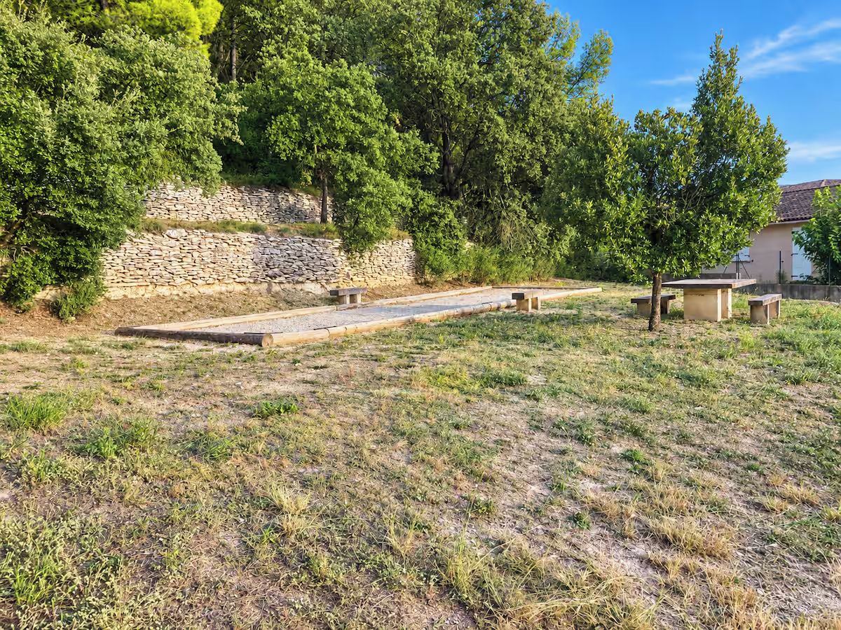 A grassy outdoor area with a stone wall and benches.