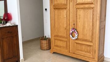 A wooden wardrobe with a mirror and a red object on a dresser.