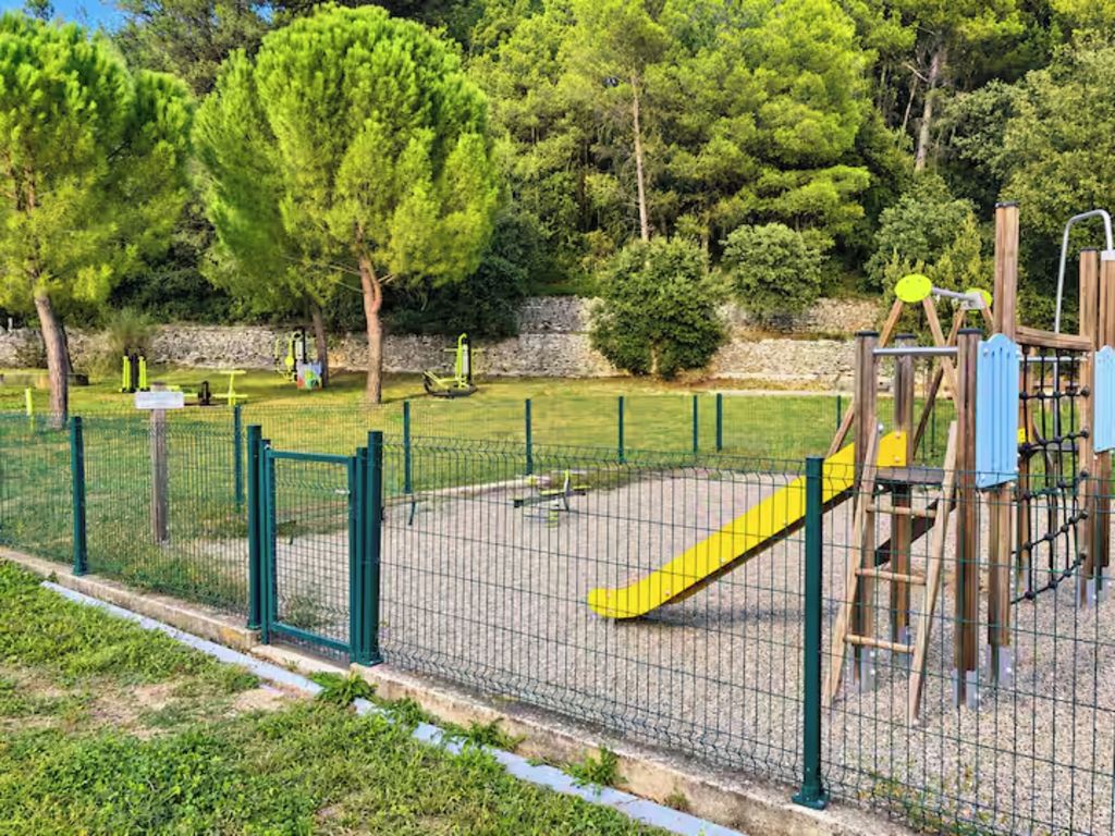 A fenced playground with a slide and climbing structures.
