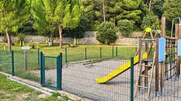 A fenced playground with a slide and climbing structures.