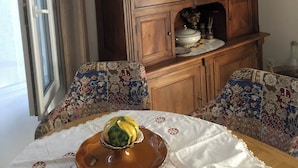 Een eethoek met een houten kast, gestreepte stoelen en een tafel met een decoratief bord.