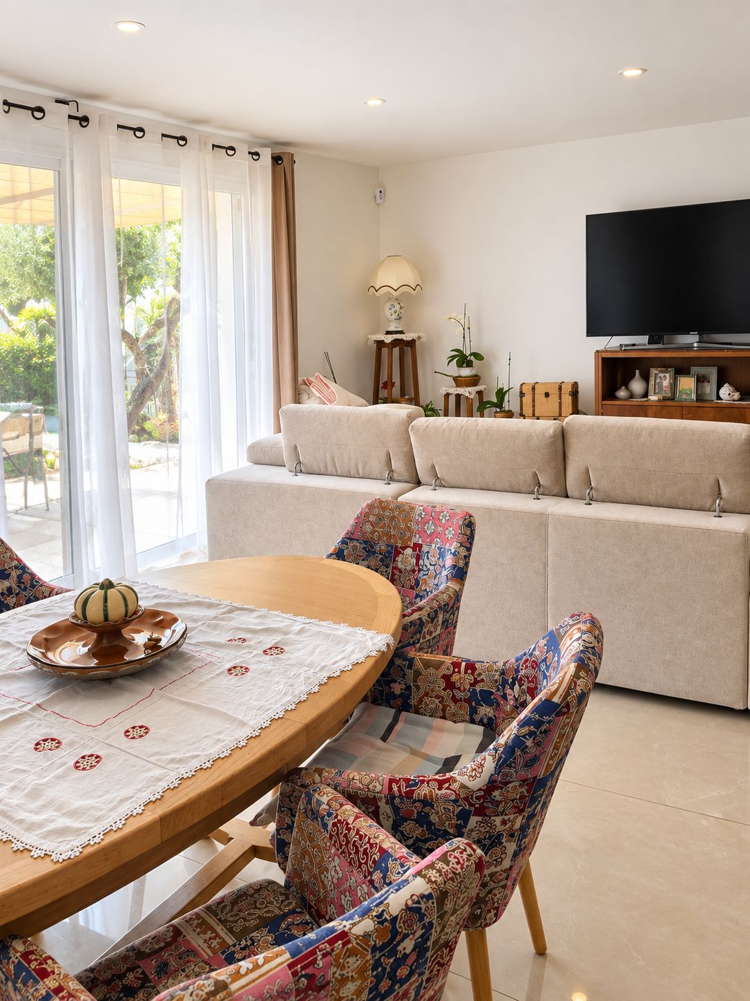 A living room with a sofa, a television, and a dining area with a table and chairs.