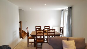 Un comedor con una mesa, sillas, una escalera y un sofá.