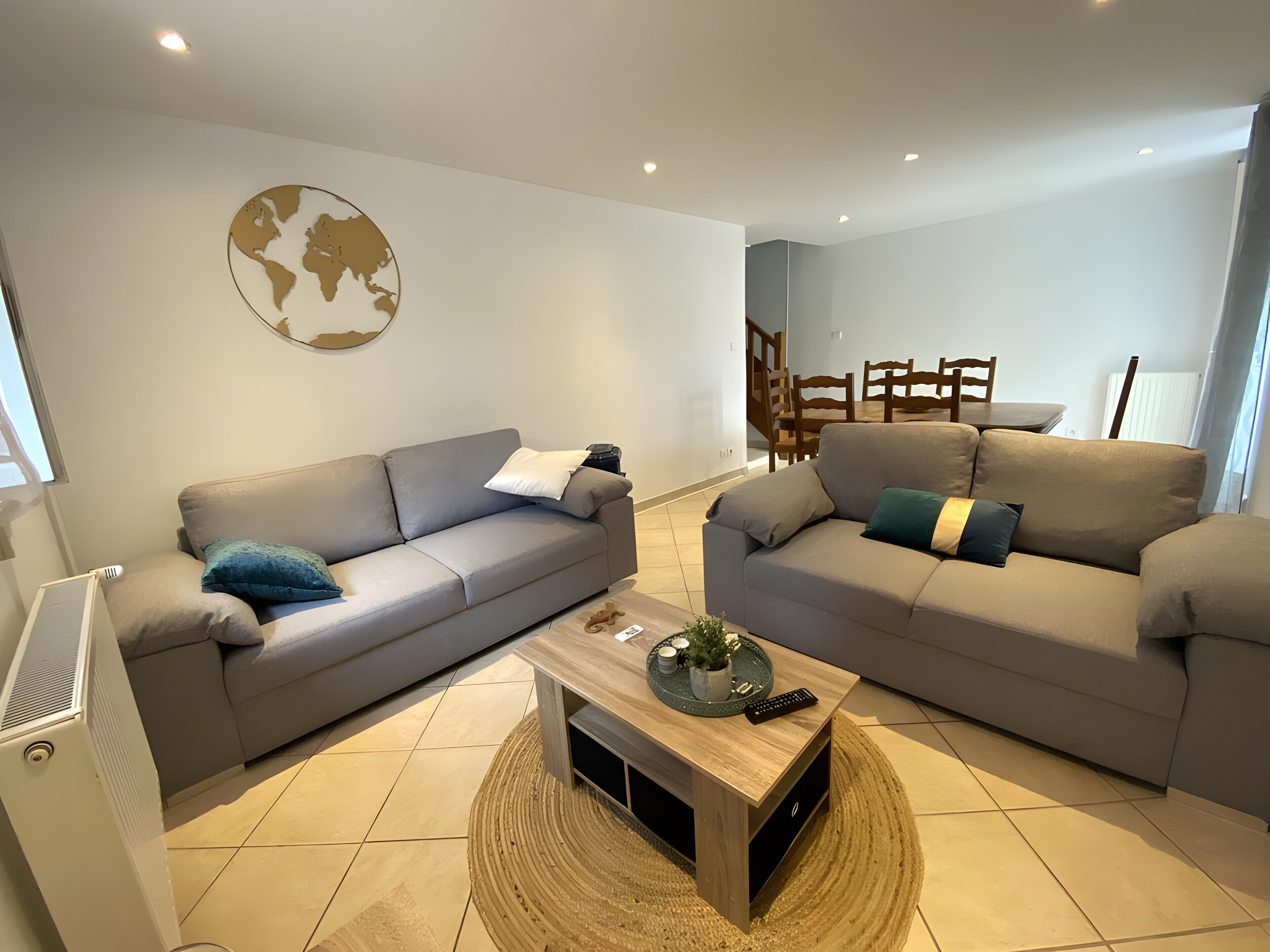 A modern living room with two sofas, a coffee table, and a dining area in the background.