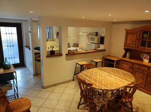 Una cocina moderna con comedor, que incluye una mesa redonda con sillas, horno empotrado y microondas.