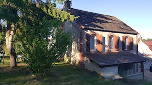 A building with a sloped roof, brick walls, and a small porch with a railing.