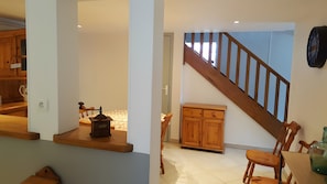 A room with a wooden staircase, a wooden cabinet, and a small table with a kettle.