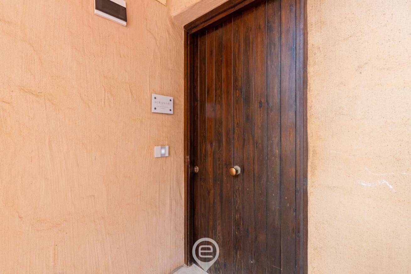 A wooden door with a metal handle and a small sign above it.