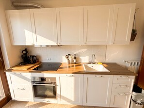 Eine Küche mit weißen Schränken, einer Holz Arbeitsplatte, einem eingebauten Ofen und einem Spülbecken.