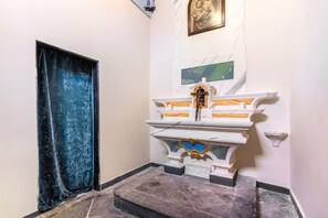 A small chapel with a marble altar, a closed door with a blue curtain, and a religious painting on the wall. - Hostdomus - Villa Celestia (Alassio)