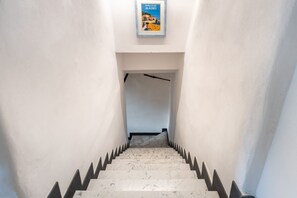 Una escala amb acabat de marbre i detalls negres al vorell, que porta a una porta.