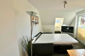 A compact room with a bed, a television, a desk, and a plant. - Holiday apartment with 3 bedrooms (Großenbrode)