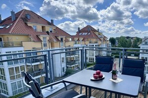 A balcony with a table, chairs, and a bottle of champagne. - Holiday apartment with 3 bedrooms (Großenbrode)