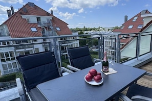 A balcony with a table, chairs, and a bottle of champagne. - Holiday apartment with 3 bedrooms (Großenbrode)