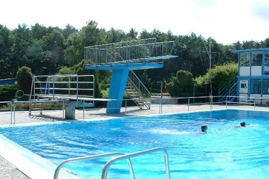 Ein Schwimmbecken mit Sprungbrett und Rettungsturm.
