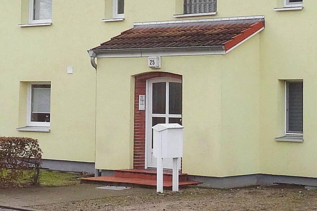 A building with a yellow facade, a red-tiled roof, and a white mailbox.