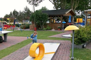 A playground with a yellow slide and a wooden playhouse. - Holiday apartment with 2 bedrooms (Schönberger Strand)