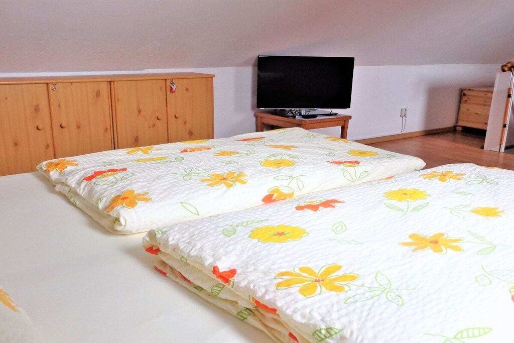 Ein Schlafzimmer mit zwei Betten, einem Fernsehgerät auf einem Schrank, Holzschränken und einem Kleiderschrank.