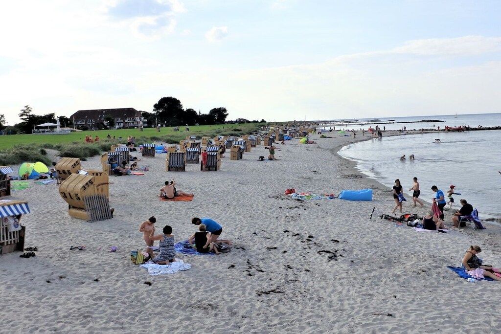 En strand med mange strandhuse og folk, der slapper af i sandet.