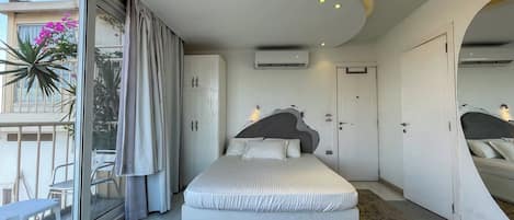 Un dormitorio moderno con una cama grande, un ventanal corredero a un balcón y un diseño de techo original.