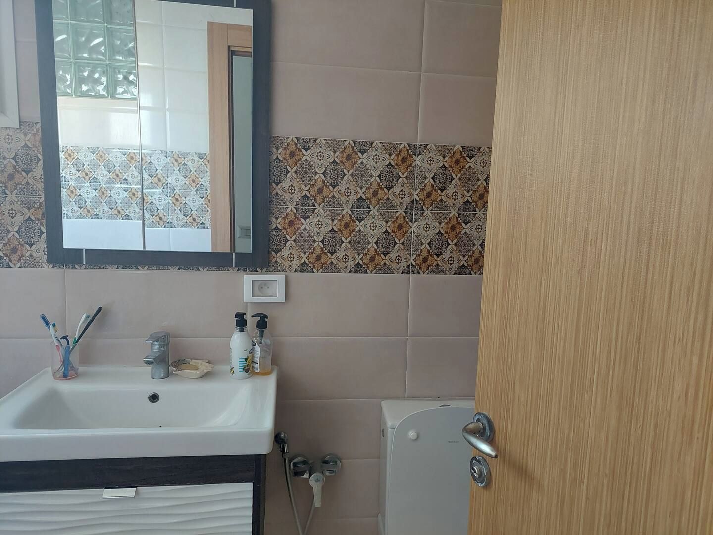 Un baño con lavamanos, espejo e inodoro.