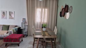 A dining area with a table set for four, a sofa with a red plaid throw, and a plant on the table. - Dar Jasmin: Chic and bright apartment in Marsa (Marsa)