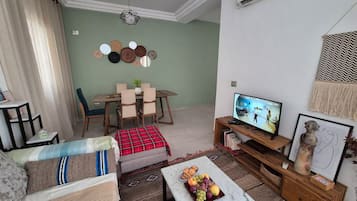 Un soggiorno con zona pranzo, televisore e parete decorata con piatti.