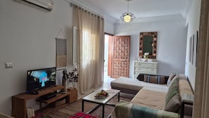 A living room with a television, a sofa, a coffee table, and a decorative mirror. - Dar Jasmin: Chic and bright apartment in Marsa (Marsa)