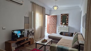 Ein Wohnzimmer mit Fernseher, einer Couch, einem Couchtisch und einem dekorativen Spiegel.