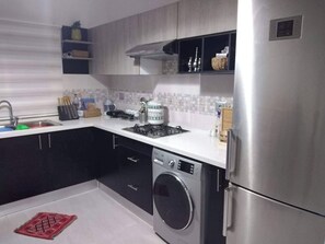 A modern kitchen with a stainless steel refrigerator, a built-in washing machine, and a gas stove. - Dar Jasmin: Chic and bright apartment in Marsa (Marsa)