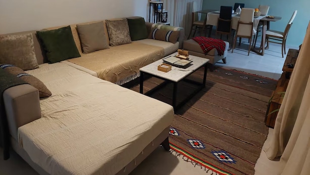 A living room with a sofa, coffee table, and a dining area with chairs and a table. - Dar Jasmin: Chic and bright apartment in Marsa (Marsa)