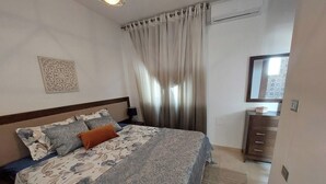 A bedroom with a bed, a nightstand, a dresser, a mirror, and a window with curtains. - Dar Jasmin: Chic and bright apartment in Marsa (Marsa)