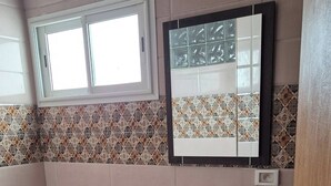 A bathroom with a bathtub, sink, and mirror. - Dar Jasmin: Chic and bright apartment in Marsa (Marsa)