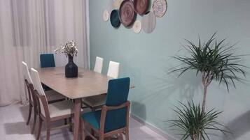 A dining area with a wooden table, six chairs, a vase with flowers, and a wall-mounted decorative plate arrangement.
