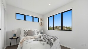 Ein Schlafzimmer mit einem Bett, zwei Nachttischen, einem Fenster und Blick ins Freie.