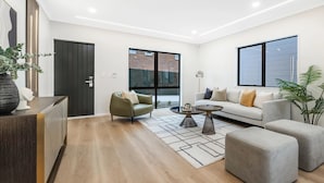 Ein modernes Wohnzimmer mit einer Couch, Sesseln, einem Couchtisch und einem Teppich.
