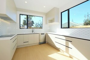 A modern kitchen with white cabinetry, a large window, and a view of the outdoors.