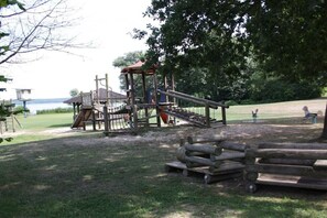 A playground with a wooden climbing structure and slides, surrounded by grass and trees. - Holiday home Butterfly (Plau am See)
