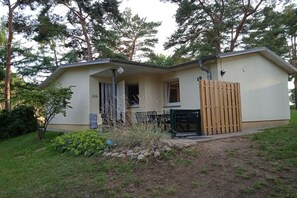 A single-story house with a front porch, a small attached garage, and a wooden fence. - Holiday home Butterfly (Plau am See)