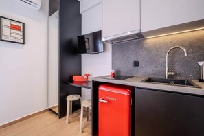 A modern kitchen with a built-in stove, a sink, and a red refrigerator. - Fun Studio for urban Explorers next to Acropolis (Athens)