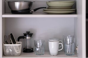 A kitchen shelf with cookware, plates, a coffee press, and glassware. - Fun Studio for urban Explorers next to Acropolis (Athens)
