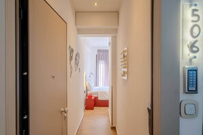 A hotel corridor with a bed, a wall-mounted control panel, and a door. - Fun Studio for urban Explorers next to Acropolis (Athens)