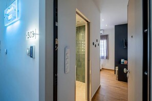 A hotel corridor with a door labeled '503', a glass door, a wall-mounted intercom, and a glimpse of a room with a window and curtains. - Fun - Sized Design studio next to Acropolis (Athens)