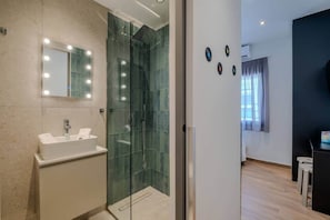 A modern bathroom with a glass-enclosed shower, a vanity with a sink, and a mirror with lights. - Fun - Sized Design studio next to Acropolis (Athens)