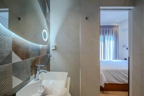 Un bany modern amb un mirall gran, un lavabo i una dutxa.