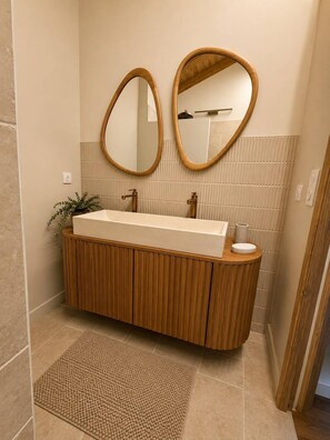 A bathroom with a wooden vanity, a large mirror, and a towel rack.