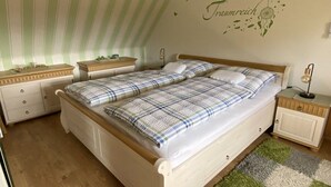 Quarto com cama de casal, mesa de cabeceira, cómoda e parede decorada com um sonho capturado.