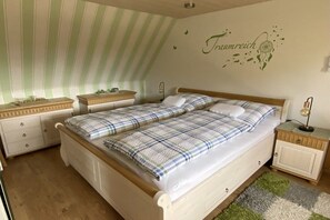 A bedroom with a double bed, a bedside table, a nightstand, a dresser, and a wall with a dreamcatcher decoration. - Holiday apartment with 1 bedroom (Ratzeburg)
